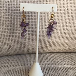 Gold tone and violet sea glass hanging earrings .
